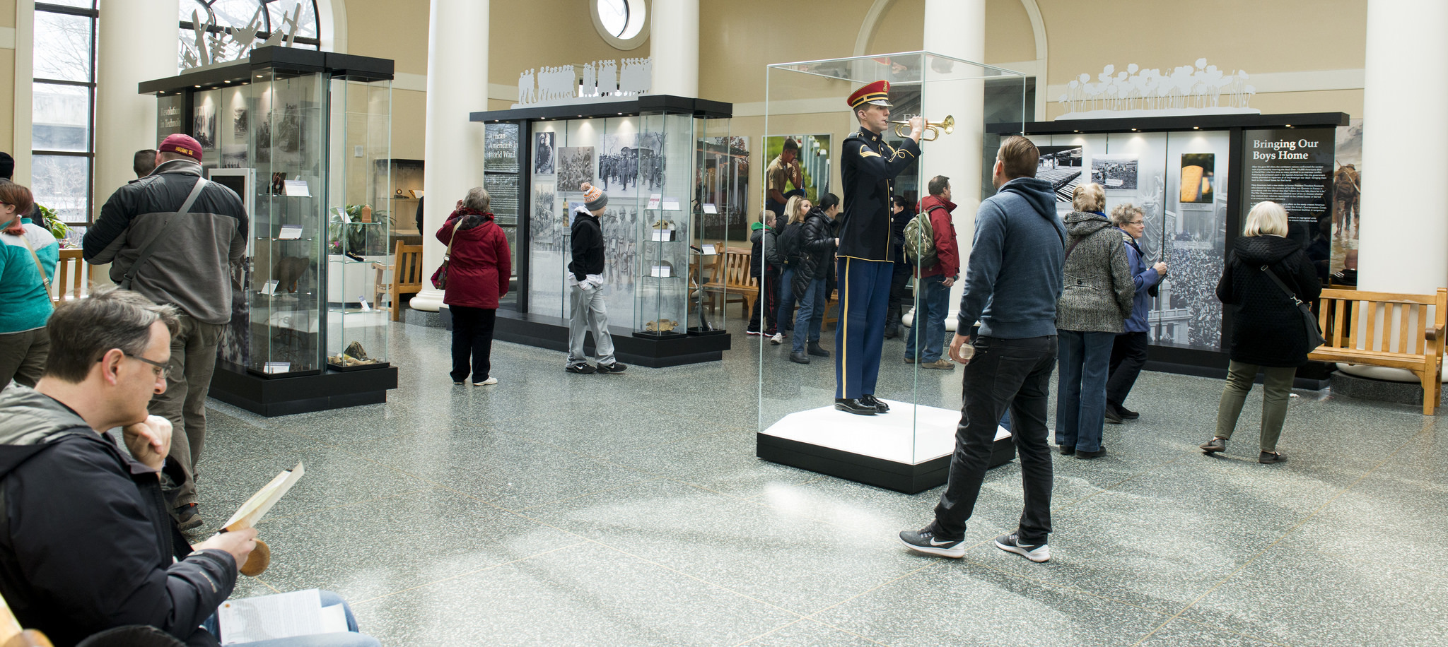 Visitors stand in front of the exhibits to read and view the photos.