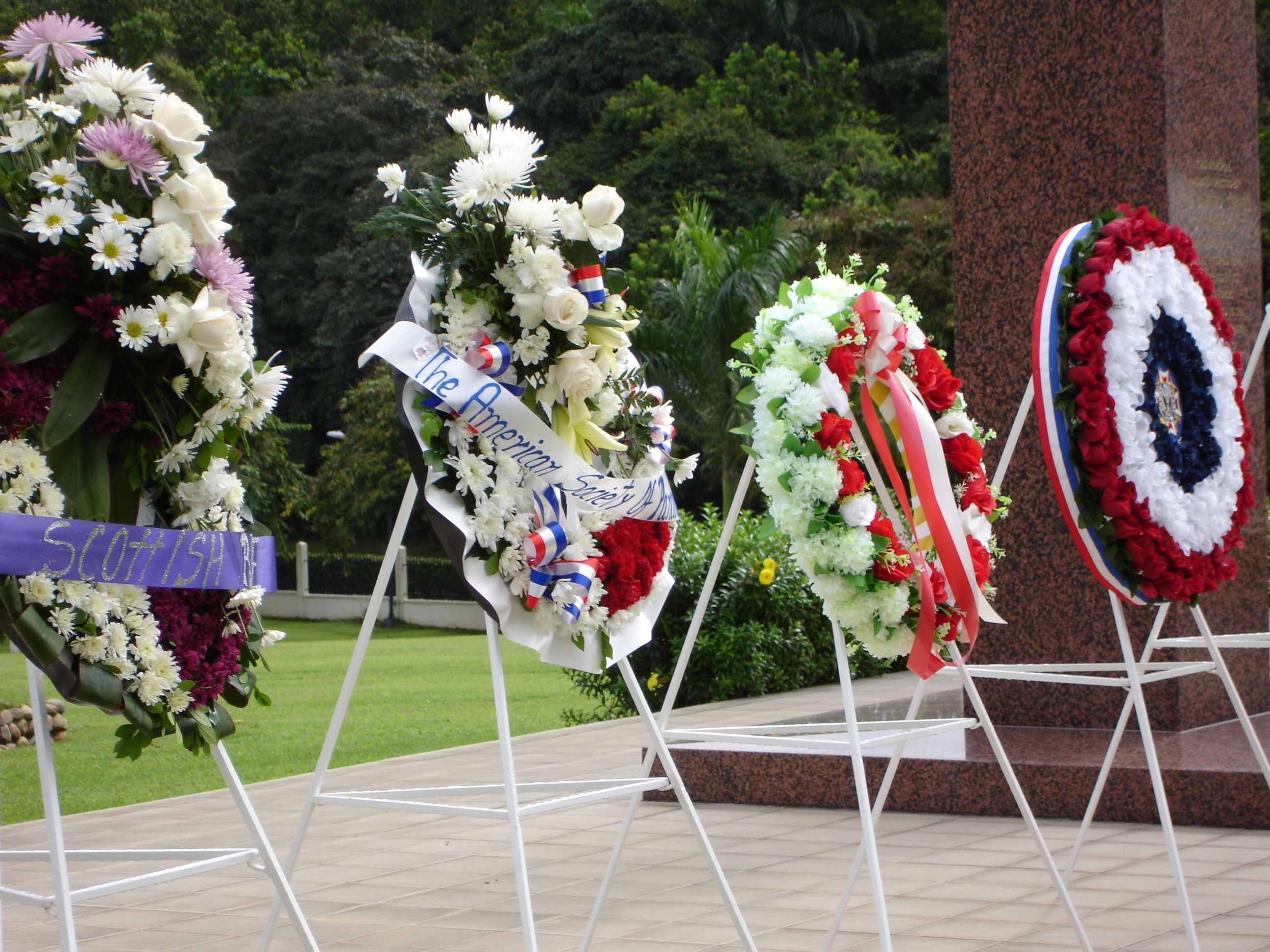 Four large floral wreaths rest on stands after the ceremony.