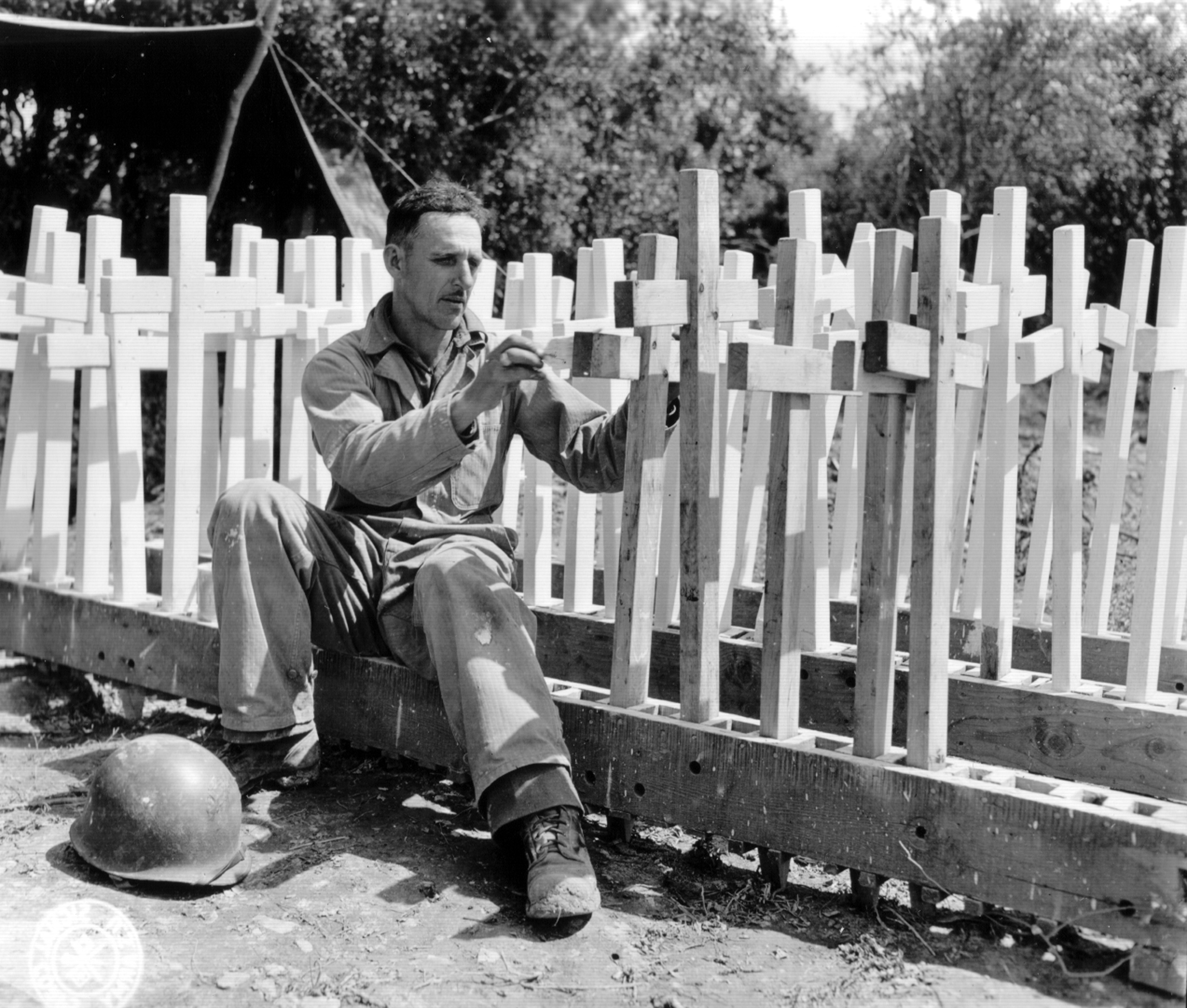 Historic photo shows soldier preparing wooden crosses.