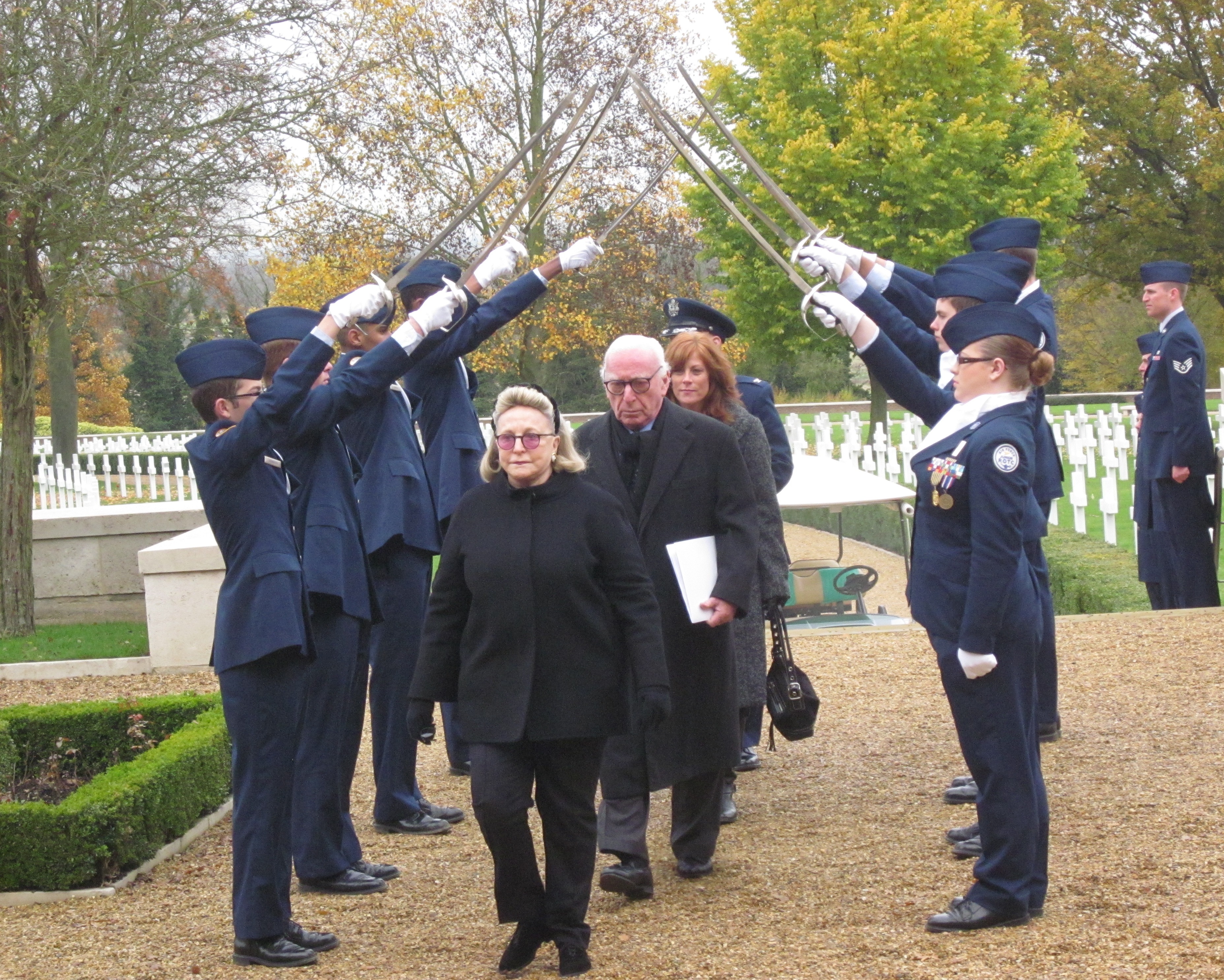 Four VIPs walk under sword-bearing men and women in uniform during 2012 Veterans Day ceremony.