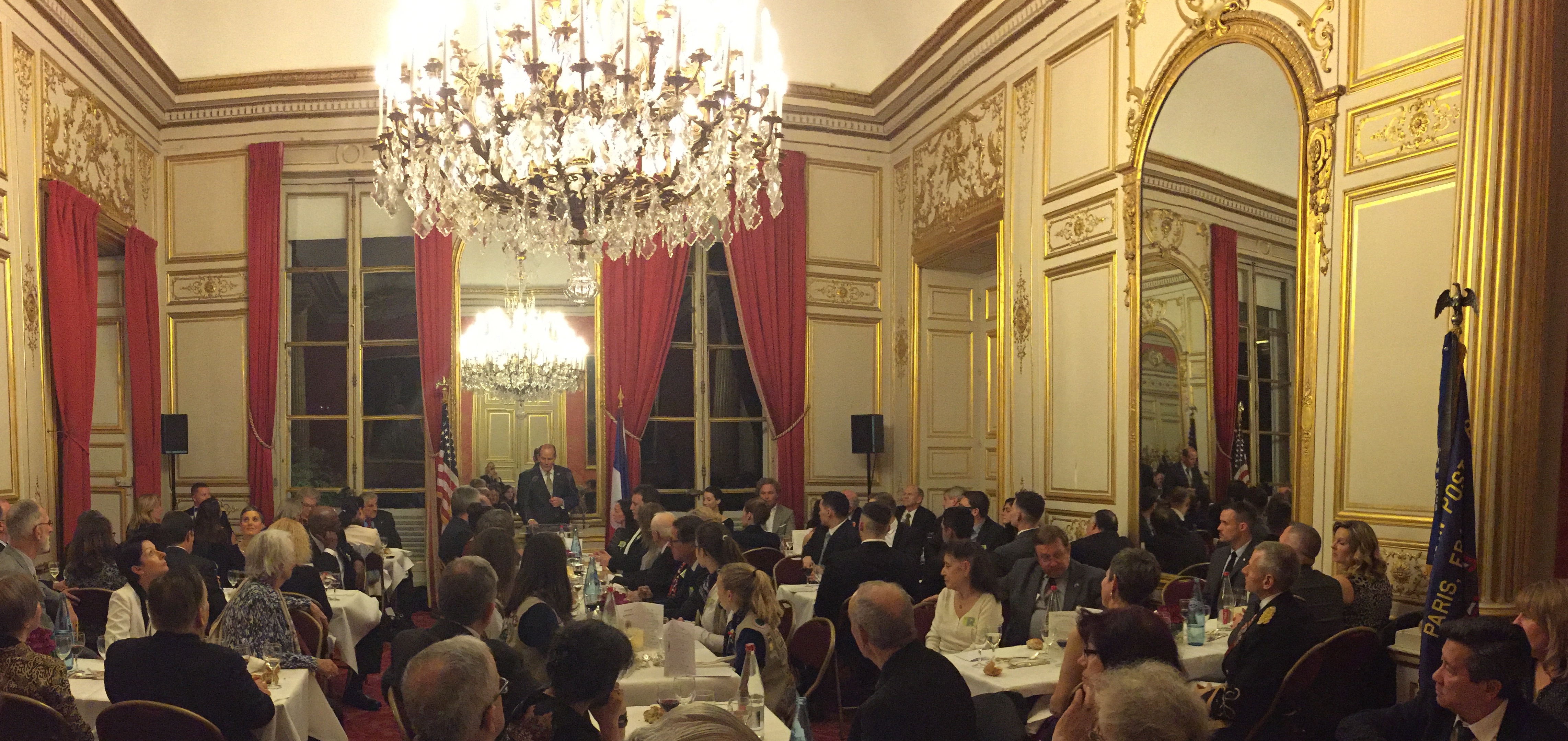 Attendees sit in an ornate room during John Wessel's speech