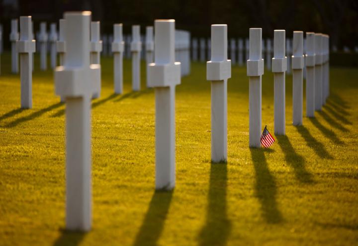 Rows of white marble cross headstones on green grass with American flag