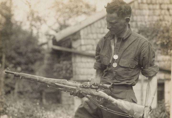 Historic photo shows man with rifle in hand. 
