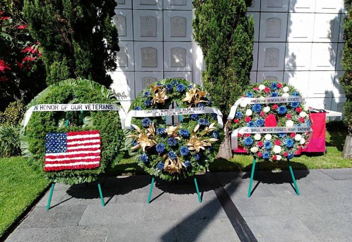 Three large floral wreaths on stands in front of the crypt. 