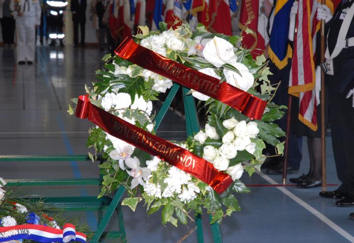 A floral wreath from the American Battle Monuments Commission rests on a stand. 