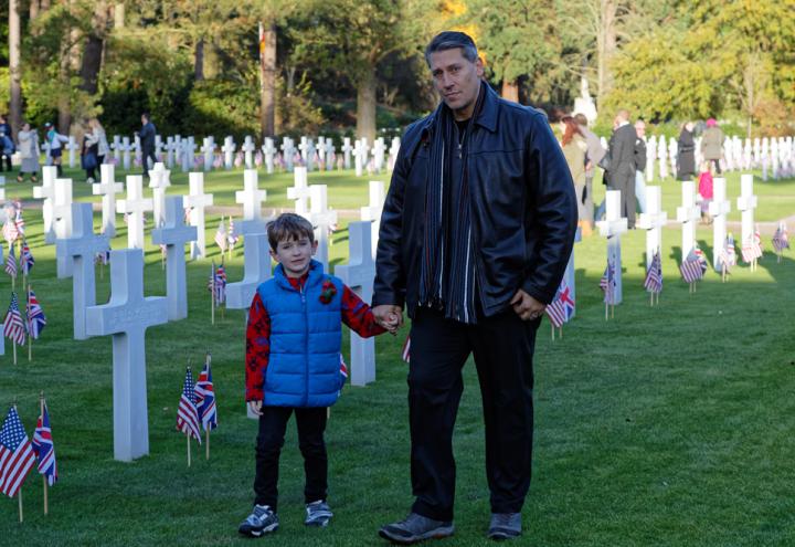 A father holds his son's hand in the plot area. 