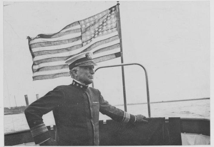 Historic photo of Wilson in uniform in front of an American flag. 
