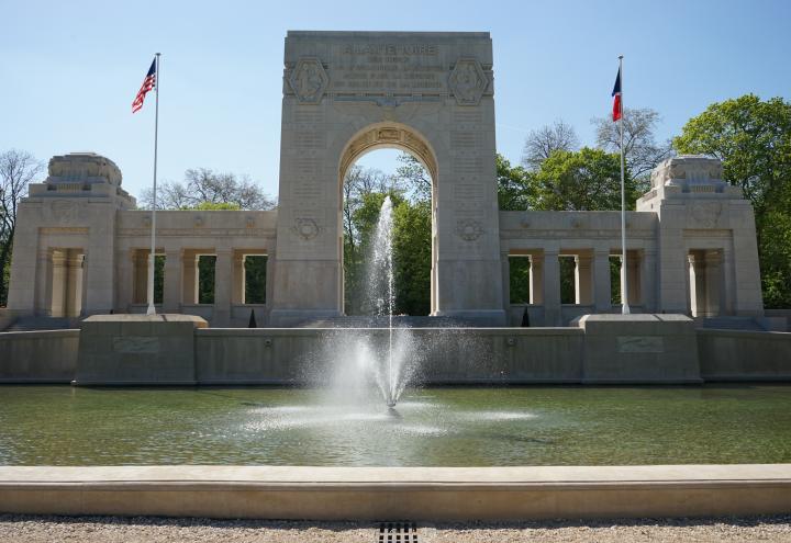 A large fountain is in front of the memorial cemetery building.