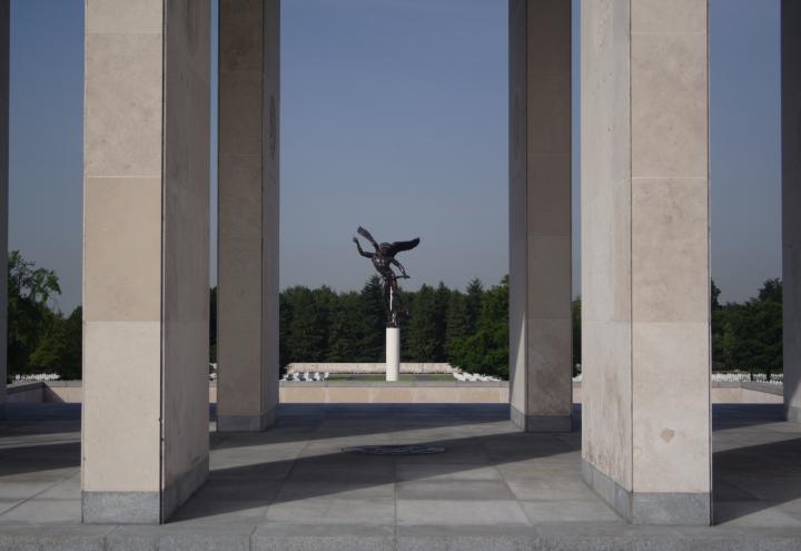 An angel statue viewed through the columns of the Henri-Chapelle American Cemetery memorial building.