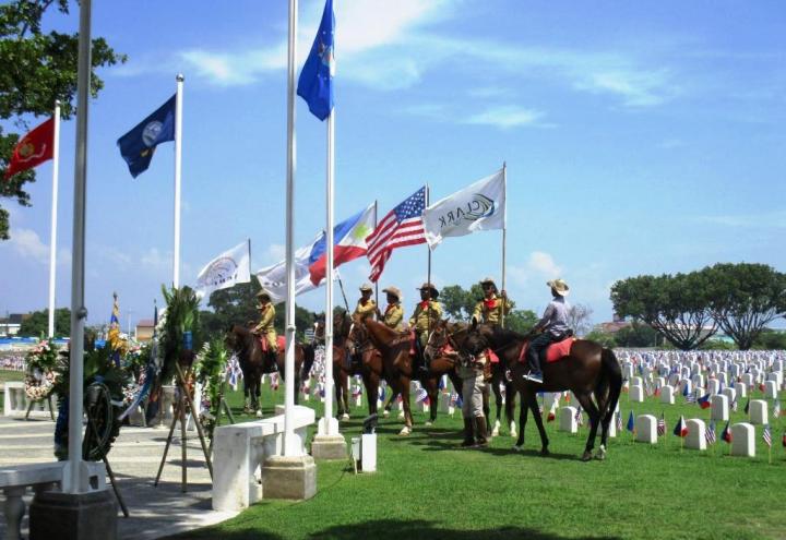 Men on horses are between the ceremony area and the plot area.