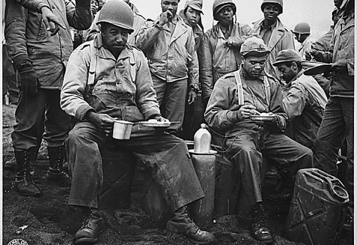 Historic photo shows men in uniform eating. 