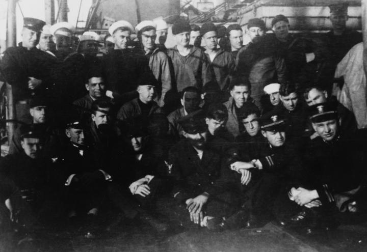 Historic photo shows men on the deck of a ship. 