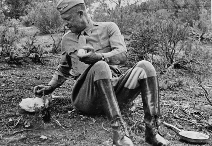 Historic photos shows Eisenhower sitting on the ground eating his lunch.