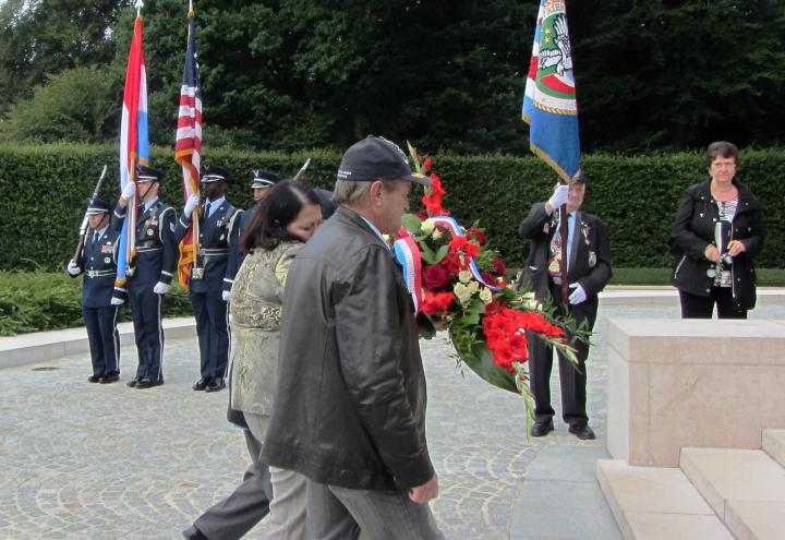 A man and a woman lay a floral wreath during the ceremony. 