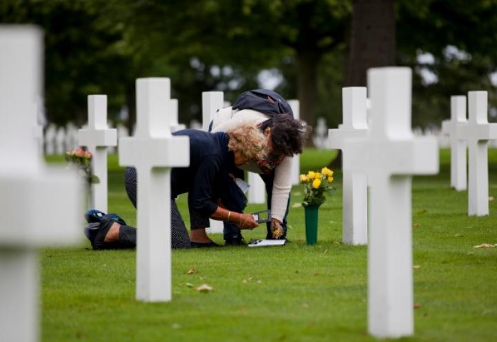Two women prepare flowers for placement at a headstone. 