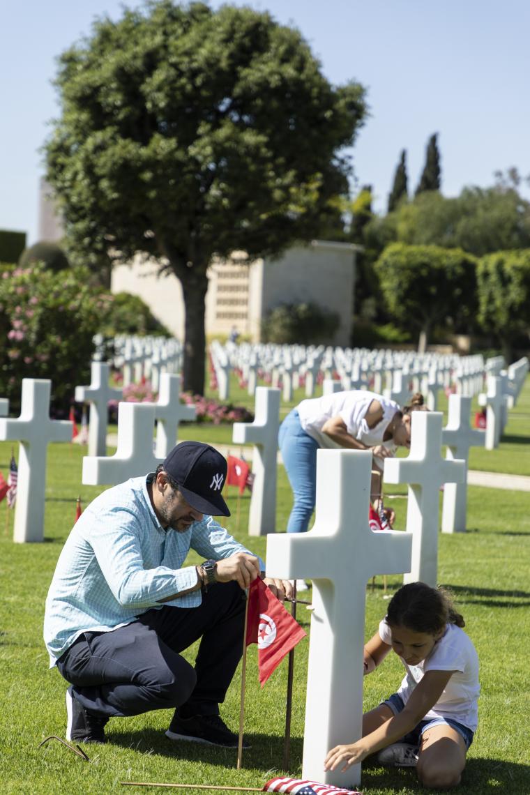Volunteers kneel down and place flags in front of the headstones. 