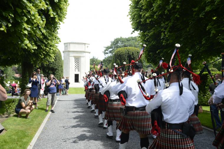 Pipers and drummers march in wearing kilts.