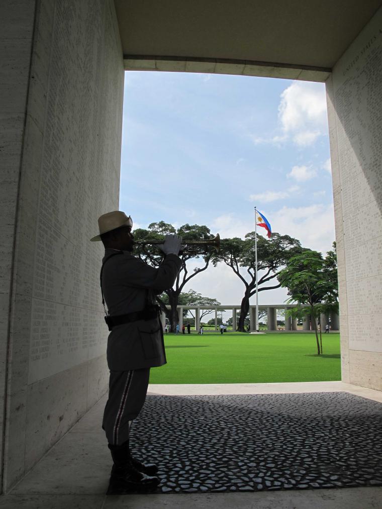 A bugler plays while standing next to the walls of the missing. 