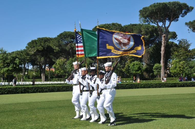 A U.S. Naval Color Guard marches with flags flying. 