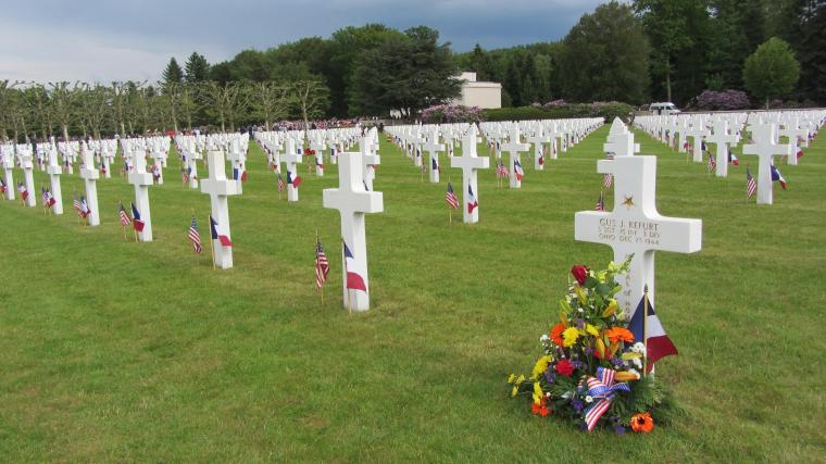 Rows of headstones have French and American flags, and some have flowers.