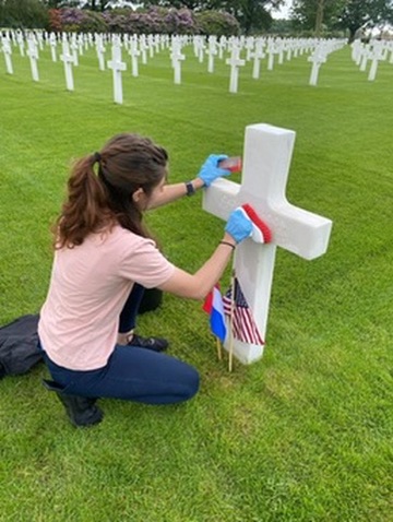 Anaiya Harris, a U.S. Air Force ROTC cadet from Brigham Young University in Provo, Utah, washes a headstone at Netherlands American Cemetery during the ABMC International Fellowship. Credits: American Battle Monuments Commission.
