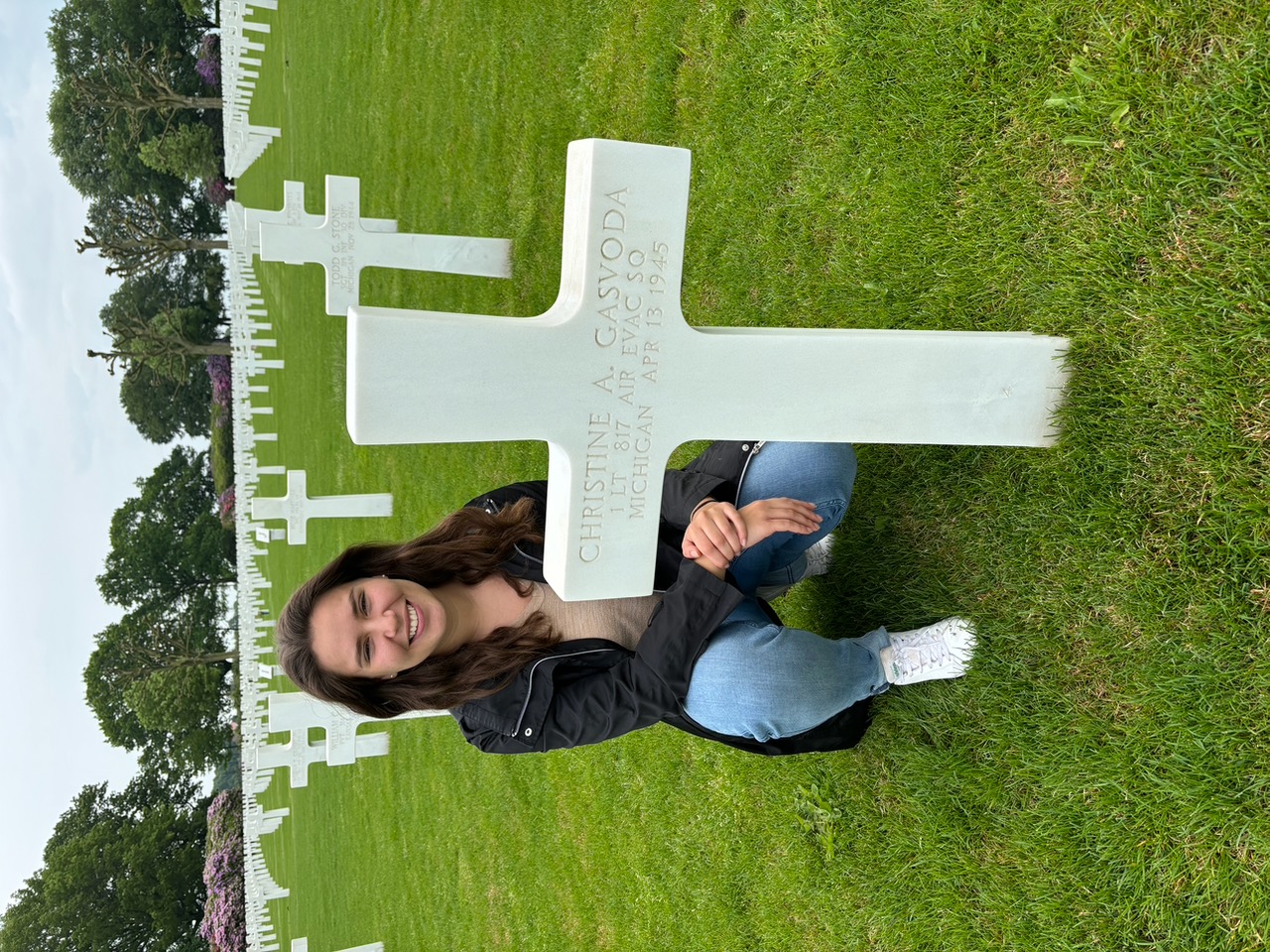 U.S. Air Force ROTC cadet and ABMC International Fellow Catherine Prince poses next to the headstone of 1st Lt. Christine A. Gasvoda. While learning more about the service members buried at the site, Prince learned one of the four women buried there was a native of a town near her home. Credits: American Battle Monuments Commission.