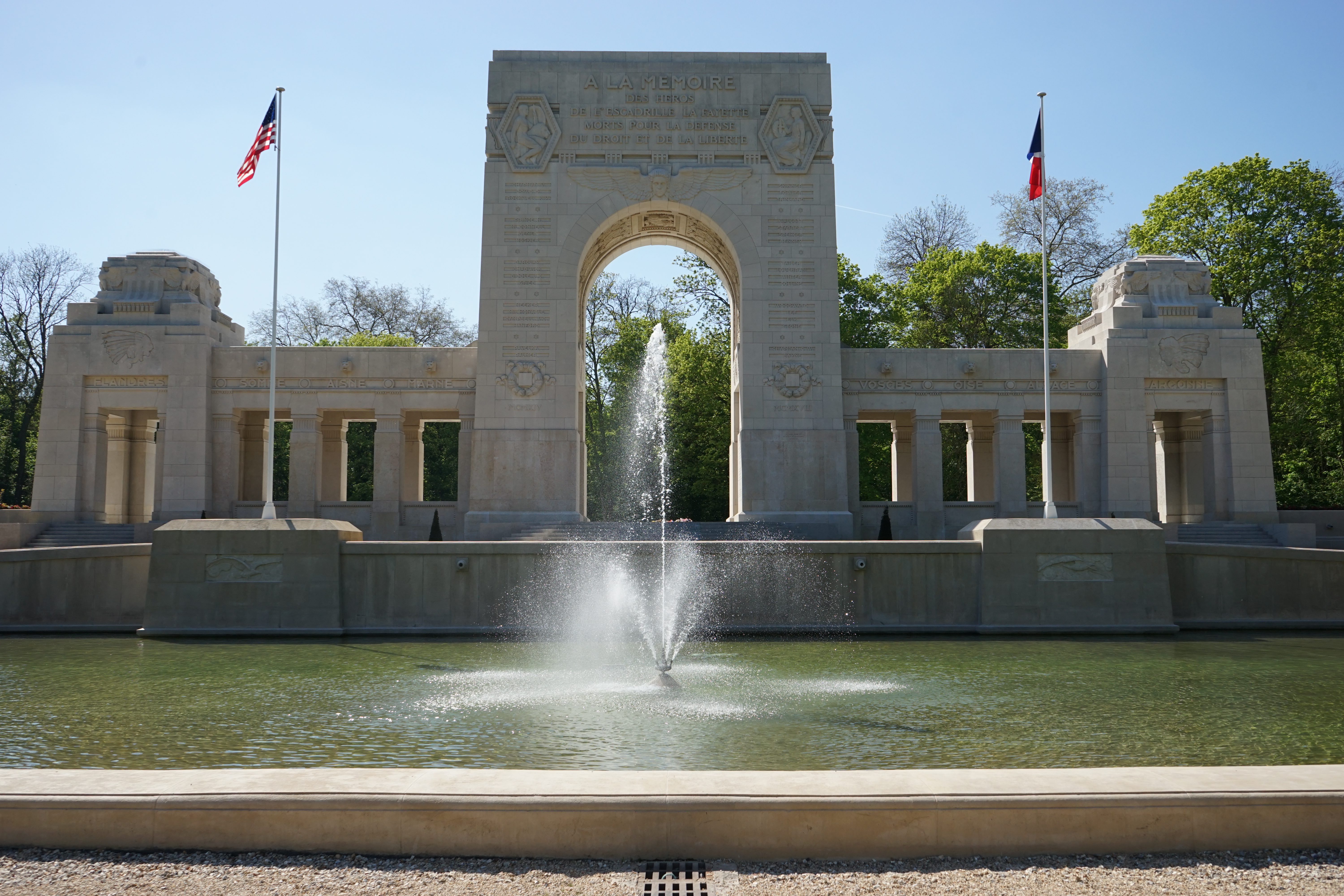 A large fountain is in front of the memorial cemetery building.