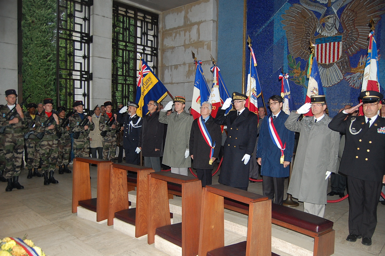 Participants salute in the chapel in front of a mosaic wall during the 2012 Veterans Day ceremony at Rhone American Cemetery. 