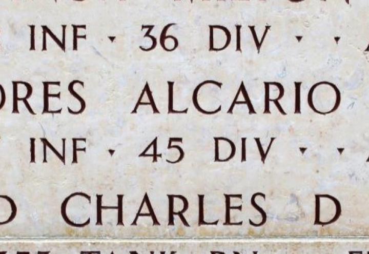 The engraved name of Alcario Flores on the wall of the missing with a bronze rosette next to the name