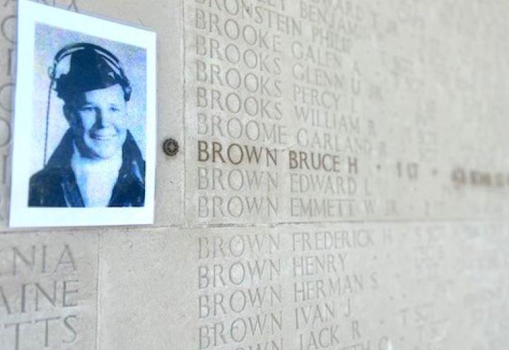 photo of Bruce Brown on a stone wall next to his engraved name 