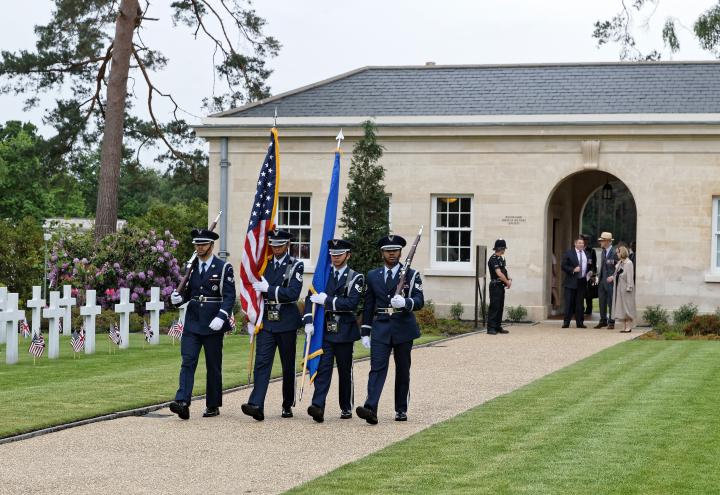 Men in uniform carry a flag or a rifle as part of the Honor Guard.