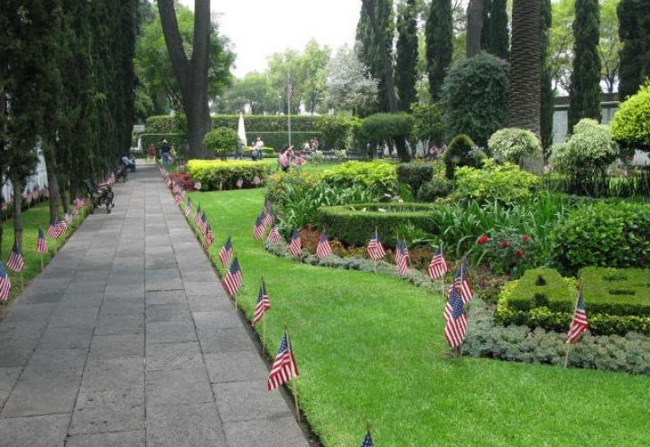 American flags line the pathway and floral beds at the cemetery. 