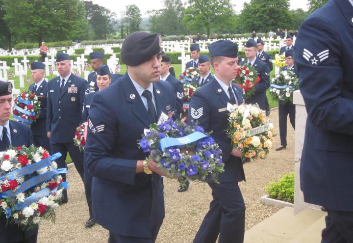 Members of the Air Force walk with small floral wreaths.