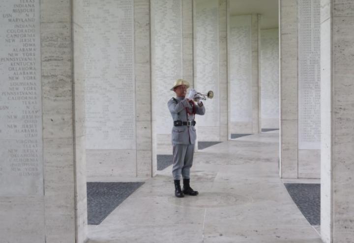 A man in uniform plays the bugle amidst the Walls of the Missing.