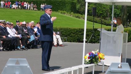 Man in uniform salutes after laying a wreath. 