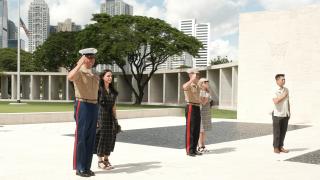 Vicente Lim IV (Vincci) Manila Visitor Center Director and Commandant of the Marine Corps General Eric M. Smith and Sergeant Major of the Marine Corps Carlos A. Ruiz and their spouses participating in a salute at the Manila American Cemetery and Memorial, with skyscrapers in the background.