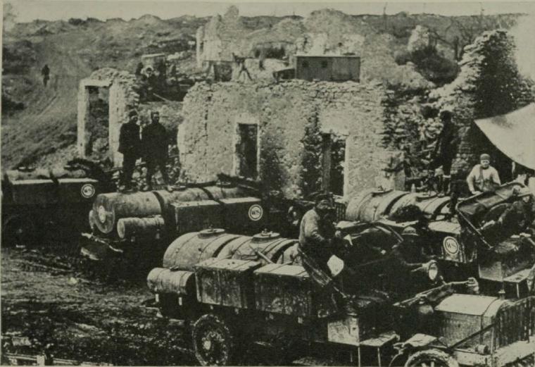 Historic image showing water trucks amongst a ruined town. 