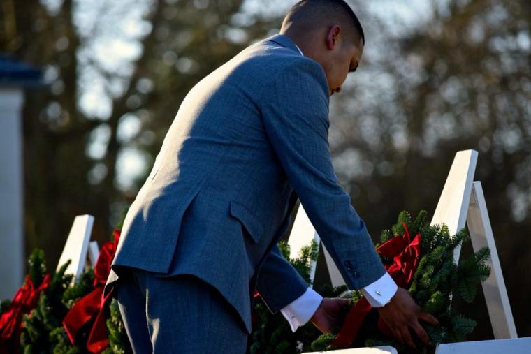 A man lays a wreath on a stand during the ceremony. 