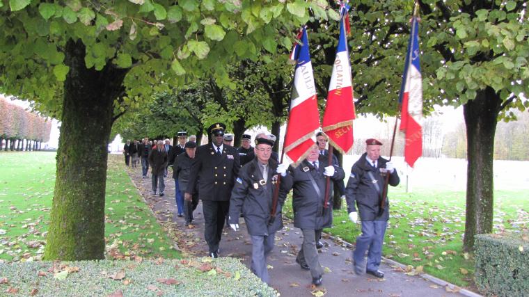 Three flag bearers lead a group of 2012 Veterans Day attendees and participants down a path at St. Mihiel American Cemetery. 