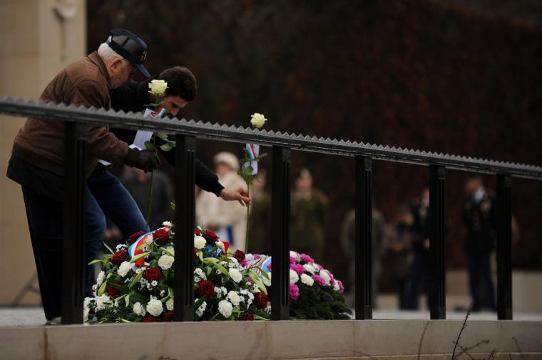 A WWII veteran along with an attendee lay white roses during the ceremony. 