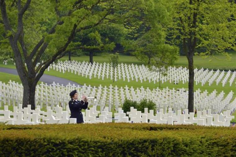 A trumpeter plays Taps amongst the headstones.