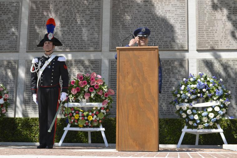 An American military official salutes from the podium. 