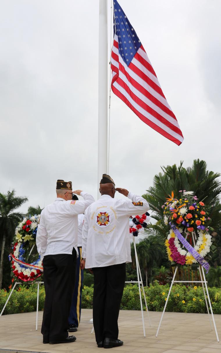 Two men salute after laying a wreath. 
