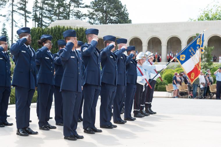Men and women in uniform salute.