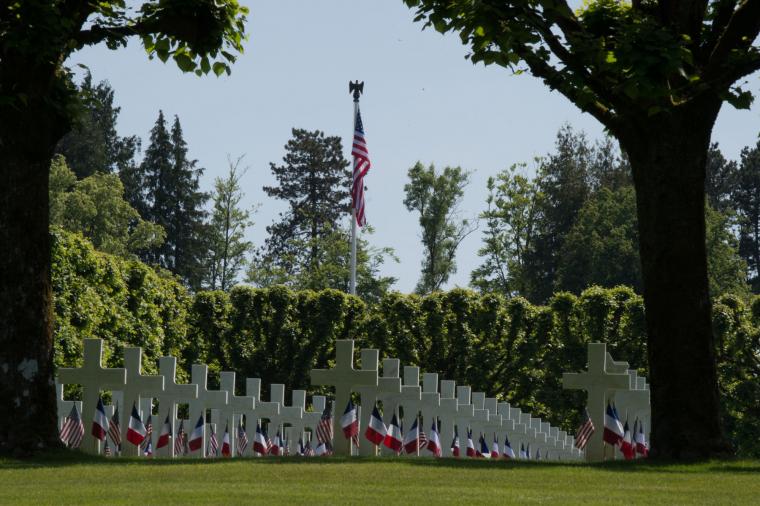 Rows of headstones with flags are seen. 