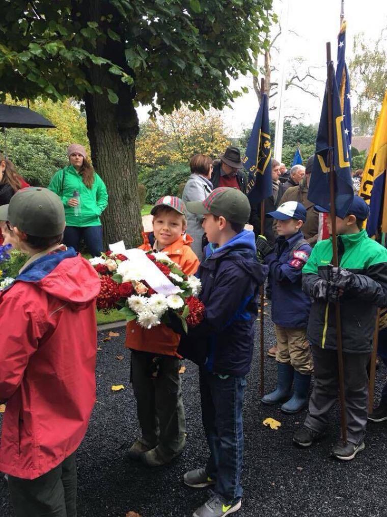 Boy Scouts hold a floral wreath and prepare to march into the cemetery.