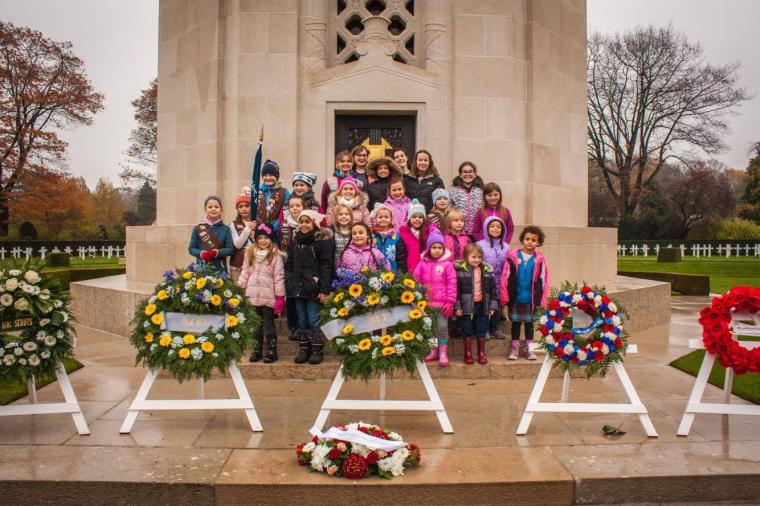 Girl scouts stand in front of the chapel, and behind the floral wreaths.