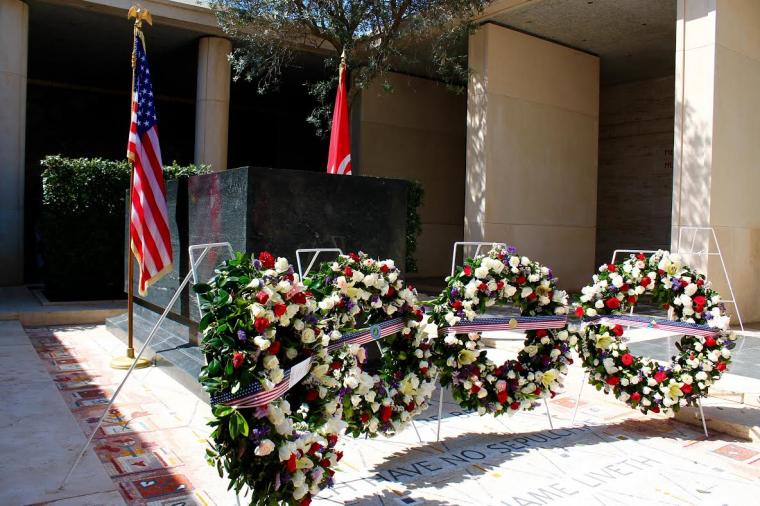 Floral wreaths are on stands within the memorial area of the cemetery.
