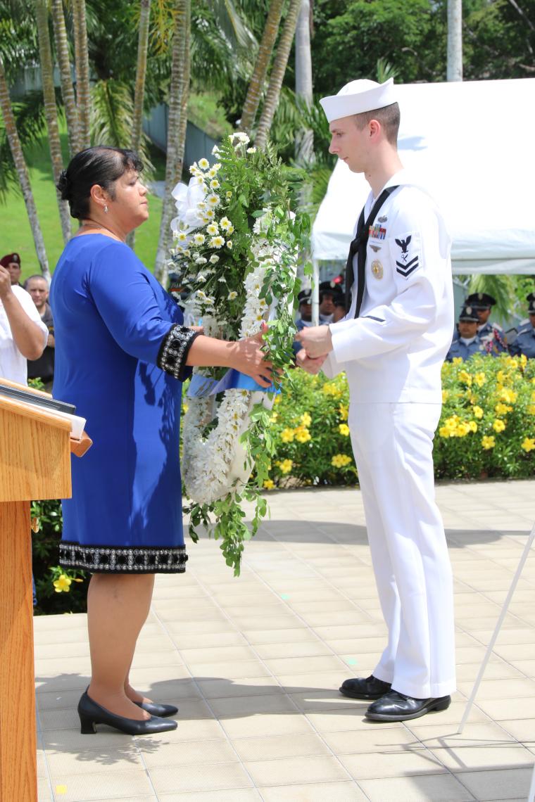 Mélanie Resto receives a large floral wreath from a sailor.