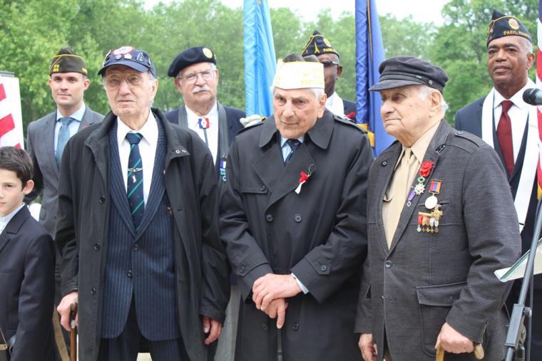 Three veterans in suits stand during the ceremony. 